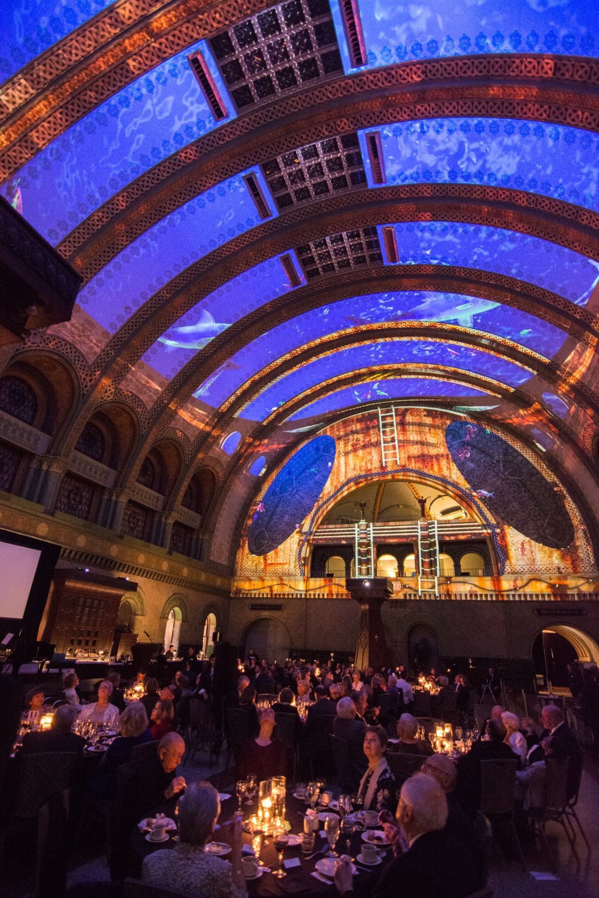Guests have dinner and watch the light show on the ceiling of the Grand Hall in Union Station